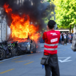 Anti-G7 protest turns violent as demonstrators torch Tesla and smash UN office windows